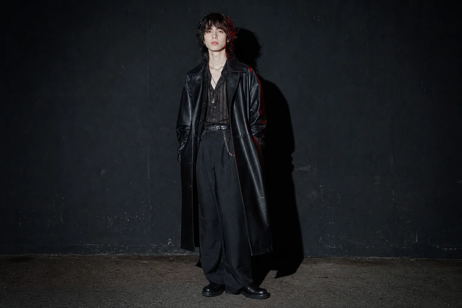 Musician in a long black coat photographed with direct flash