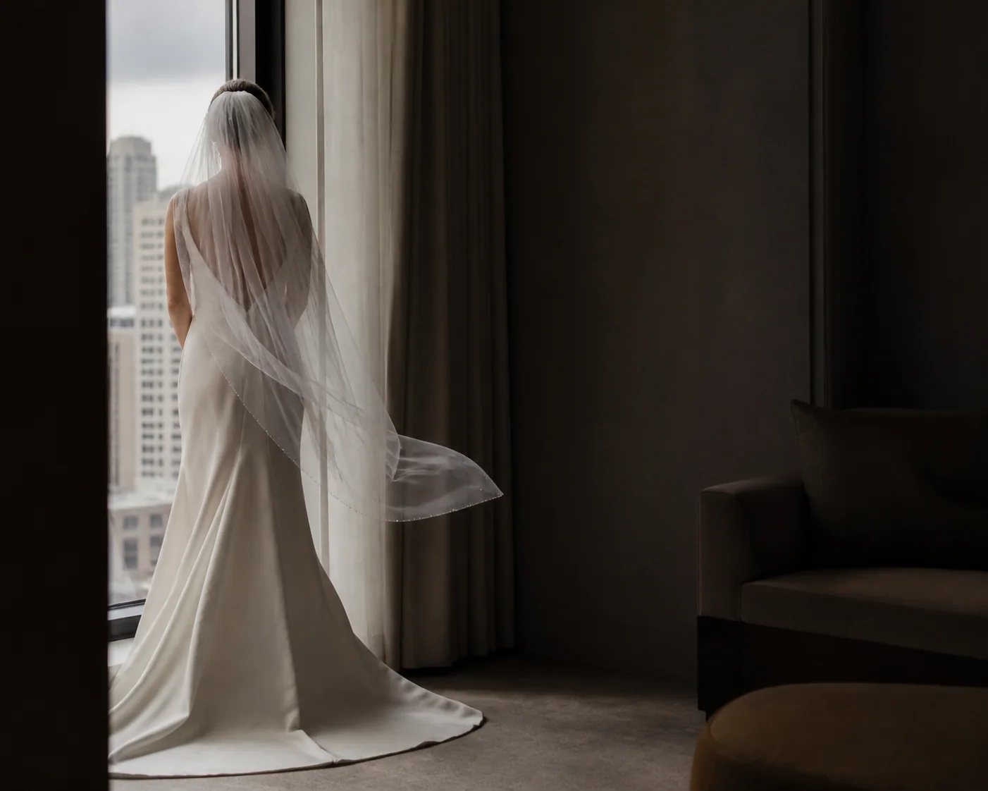 Bride in a veil standing beside a hotel window